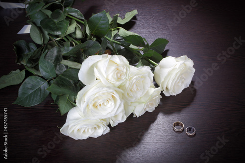 Bouquet of white roses and wedding rings on the table