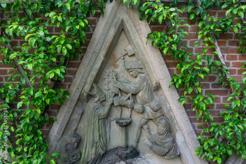 Religious relief with a scene from the life of St. Maarten, carved on grey stone in a city garden in Utrecht