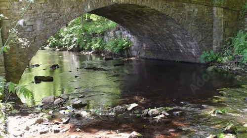 Video of bridge at the river at Rivelin Valley near Sheffield in South Yorkshire. Select focus. 4K video footage of water flowing in river.