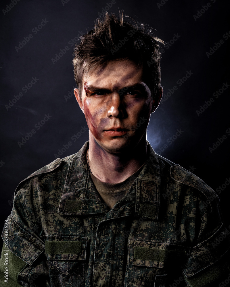 Portrait of a young soldier in uniform and combat coloring with bruises and scars on a black background Portrait of a young soldier in uniform and combat coloring with bruises and scars on a black background