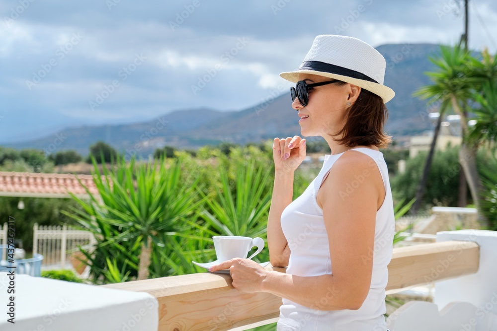 Fototapeta premium Tourism, travel, vacation, resort. Happy middle age woman in sunglasses hat with cup of coffee