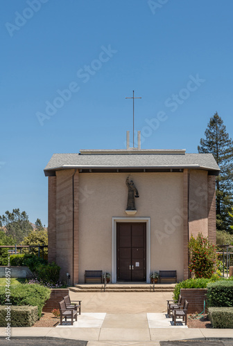 Santa Inez, CA, USA - May 26, 2021: San Lorenzo Seminary. Front facade with statue of the church under blue sky. Green garden foliage in front. photo
