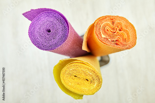 Colored corrugated craft paper, top view of three multicolored rolls.