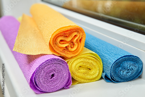 Four rolls multicolored Crepe Paper for creation lie on sill.