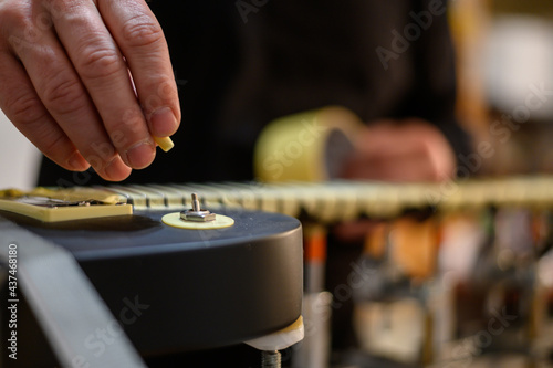 Obraz na plátně Guitar in repair service shop with a hands of a guitar luthier which fixes it