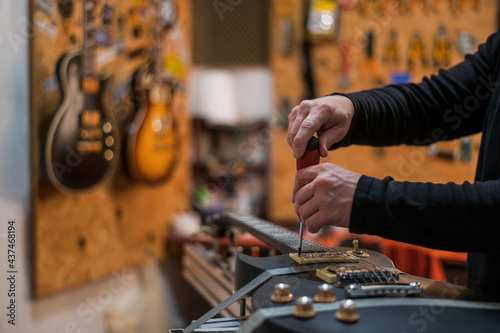 Obraz na plátně Guitar in repair service shop with a hands of a guitar luthier which fixes it