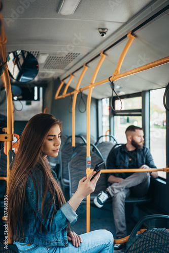 Young beautiful passengers using smartphones while riding the bus