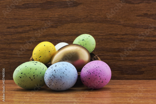 Gold egg in nest surrounded by multiple, colorful eggs symbolize success of strategic diversification in financial investing photo