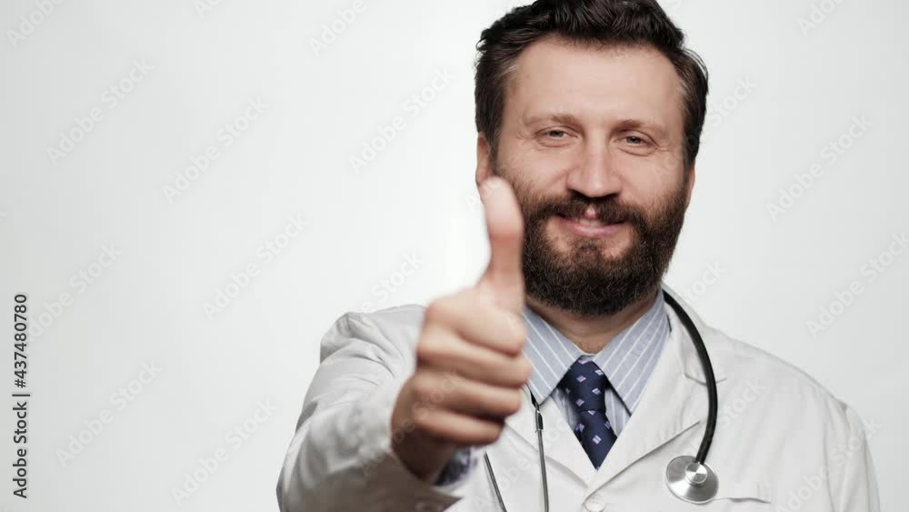 Doctor thumb up. Portrait of positive smiling man doctor on white background looking at camera and shows his thumb up Doctor thumb up. Portrait of positive smiling man doctor on white background looking at camera and shows his thumb up