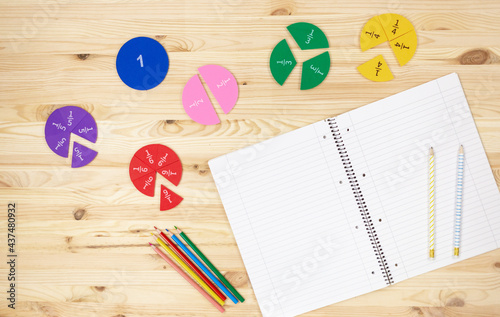 Colorful fractions in mathematics on the open notepad on wooden table. Interesting math for kids. Education, back to school concept	 photo