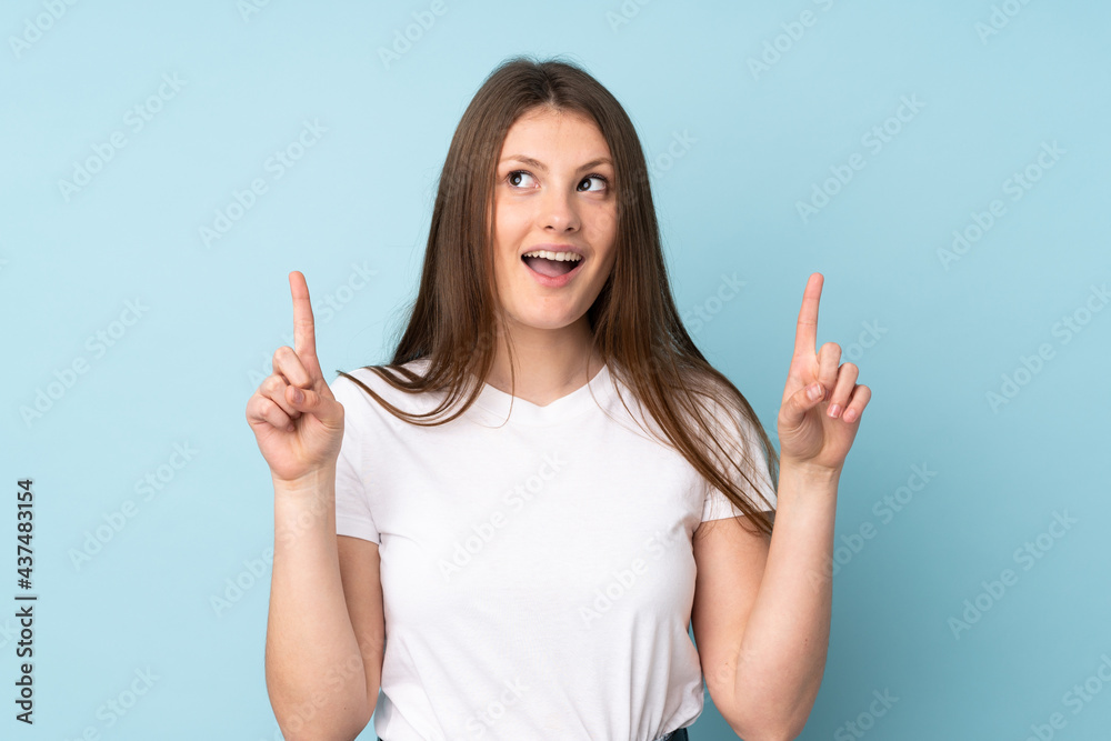 Teenager caucasian girl isolated on blue background surprised and pointing up Teenager caucasian girl isolated on blue background surprised and pointing up