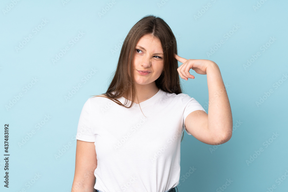 Teenager caucasian girl isolated on blue background making the gesture of madness putting finger on the head Teenager caucasian girl isolated on blue background making the gesture of madness putting finger on the head
