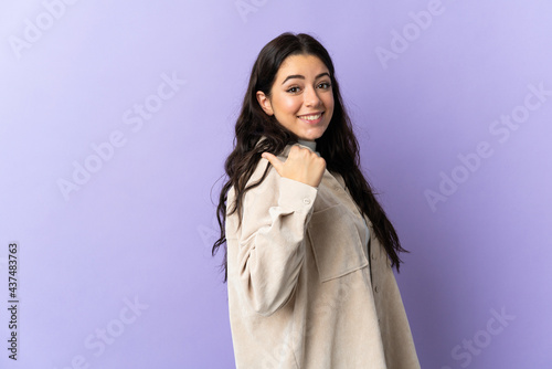 Young caucasian woman isolated on purple background pointing to the side to present a product © luismolinero