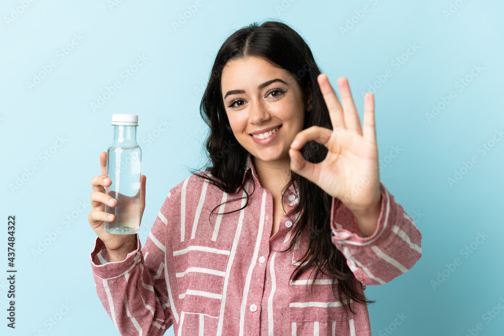 Young woman with a water isolated on blue background showing ok sign with fingers Young woman with a water isolated on blue background showing ok sign with fingers