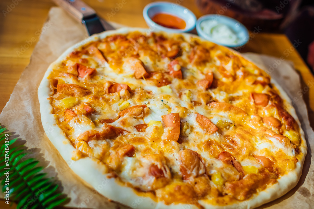 Homemade pizza on brown paper on wooden table with green leaf and white cream Homemade pizza on brown paper on wooden table with green leaf and white cream