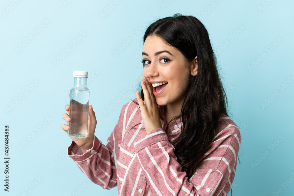 Young woman with a water isolated on blue background whispering something Young woman with a water isolated on blue background whispering something