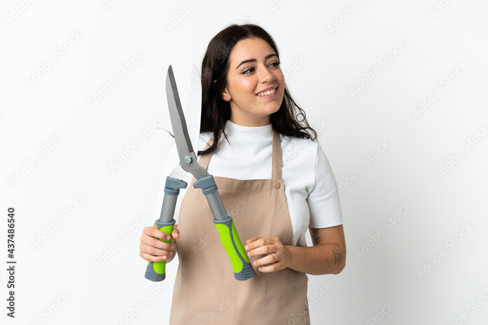Young caucasian woman holding a plant isolated on white background looking to the side and smiling Young caucasian woman holding a plant isolated on white background looking to the side and smiling