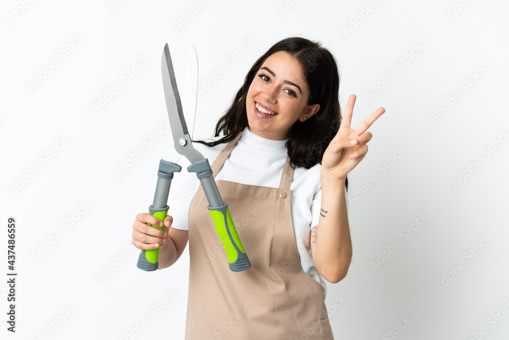 Young caucasian woman holding a plant isolated on white background smiling and showing victory sign Young caucasian woman holding a plant isolated on white background smiling and showing victory sign