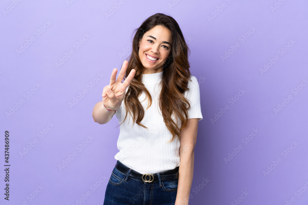 Woman over isolated purple background happy and counting three with fingers Woman over isolated purple background happy and counting three with fingers