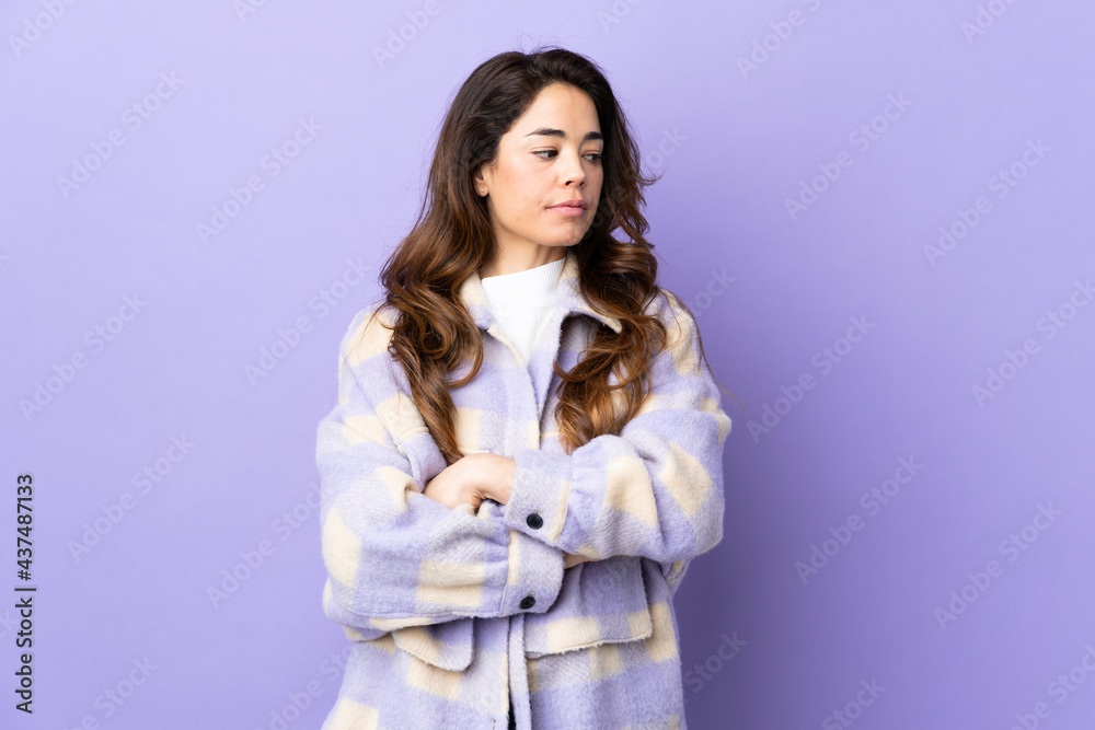 Woman over isolated purple background keeping the arms crossed