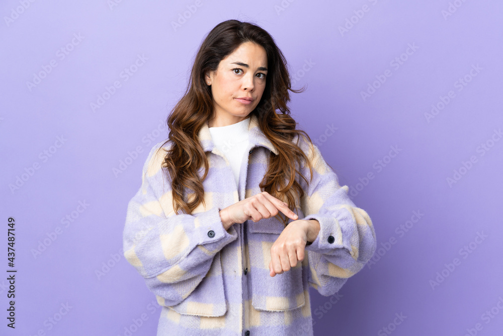 Woman over isolated purple background making the gesture of being late Woman over isolated purple background making the gesture of being late