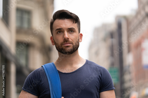 Young caucasian man on city street walking serious face