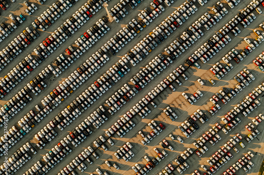 Aerial view new cars lined up in the parking station for import and export business logistic to dealership for sale, Automobile and automotive car parking lot for commercial business industry.