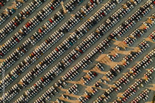 Aerial view new cars lined up in the parking station for import and export business logistic to dealership for sale, Automobile and automotive car parking lot for commercial business industry.