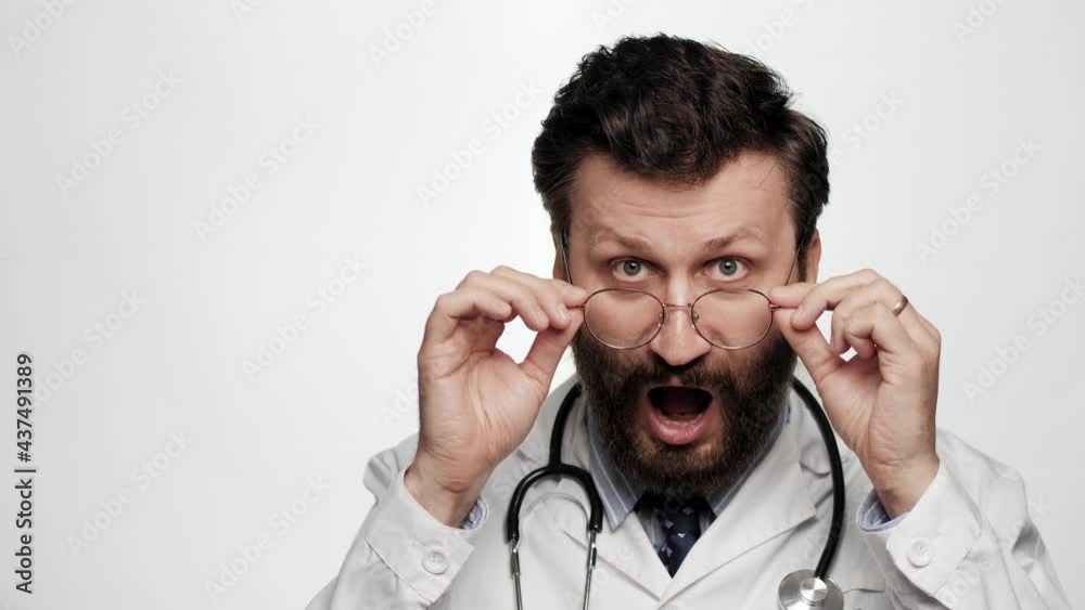 Doctor is surprised, shocked. Confused man doctor on white background takes off his glasses with surprised face and looking at camera Doctor is surprised, shocked. Confused man doctor on white background takes off his glasses with surprised face and looking at camera