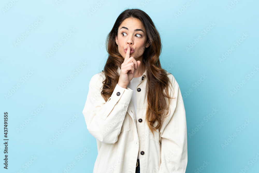 Woman over isolated background showing a sign of silence gesture putting finger in mouth Woman over isolated background showing a sign of silence gesture putting finger in mouth
