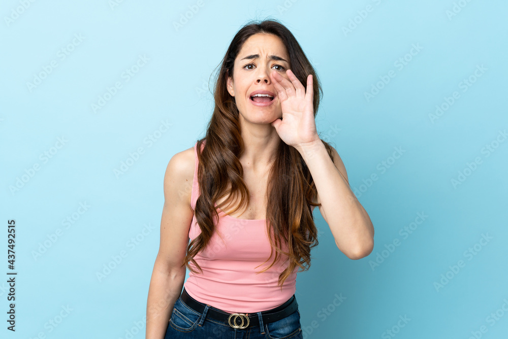 Woman over isolated blue background shouting with mouth wide open Woman over isolated blue background shouting with mouth wide open