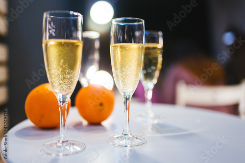 Glasses of white champagne and oranges on a white table