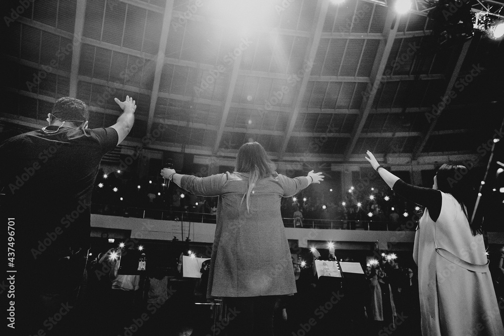 Christians raising their hands in praise and worship at a night music concert - obrazy, fototapety, plakaty 
