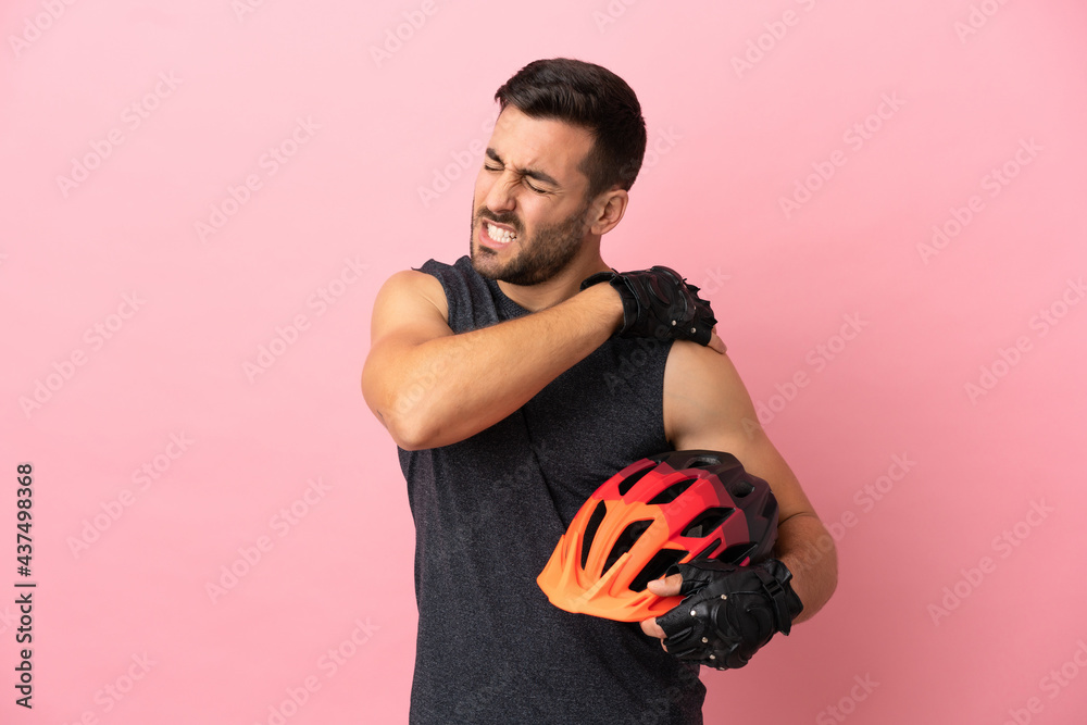 Young cyclist man isolated on pink background suffering from pain in shoulder for having made an effort - obrazy, fototapety, plakaty 