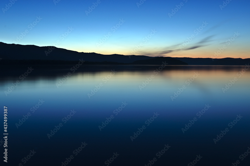 美しいグラデーションの空を静水の湖面に映す夕暮れの湖。