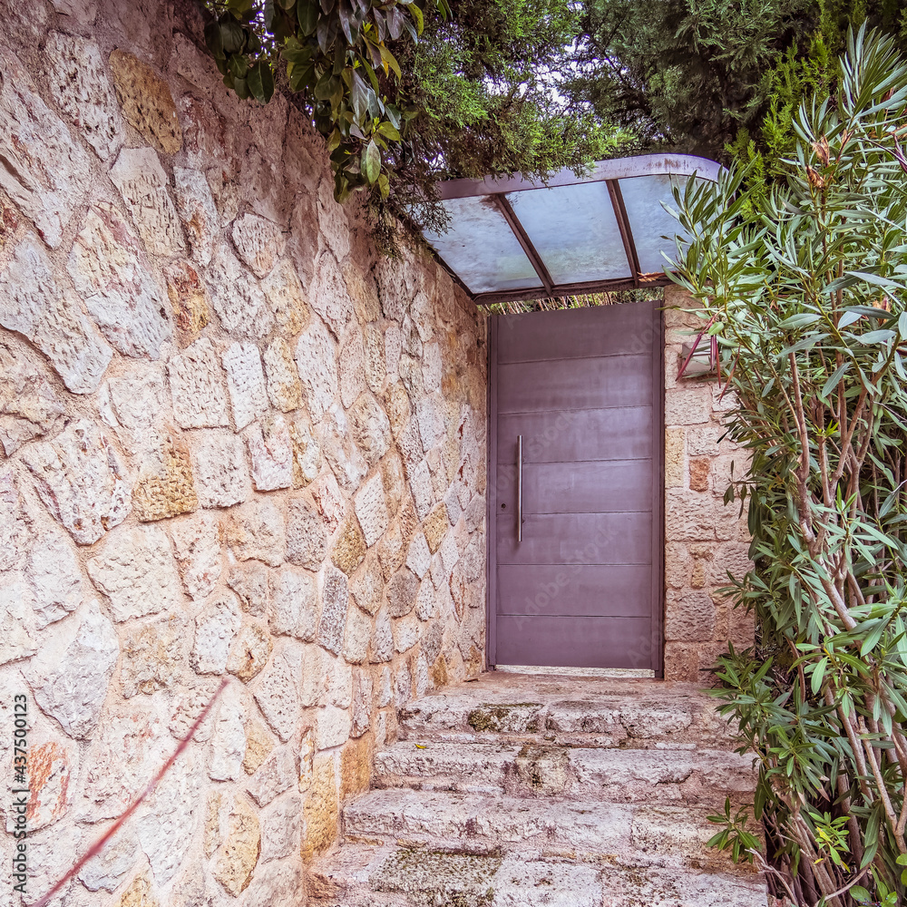 contemporary house, front stone wall fence and grey metallic entrance door contemporary house, front stone wall fence and grey metallic entrance door
