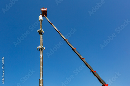 Engineer is working on thecellular phone repeater mast from An aerial work platform, also known as an aerial device, elevating work platform, cherry picker, bucket truck .