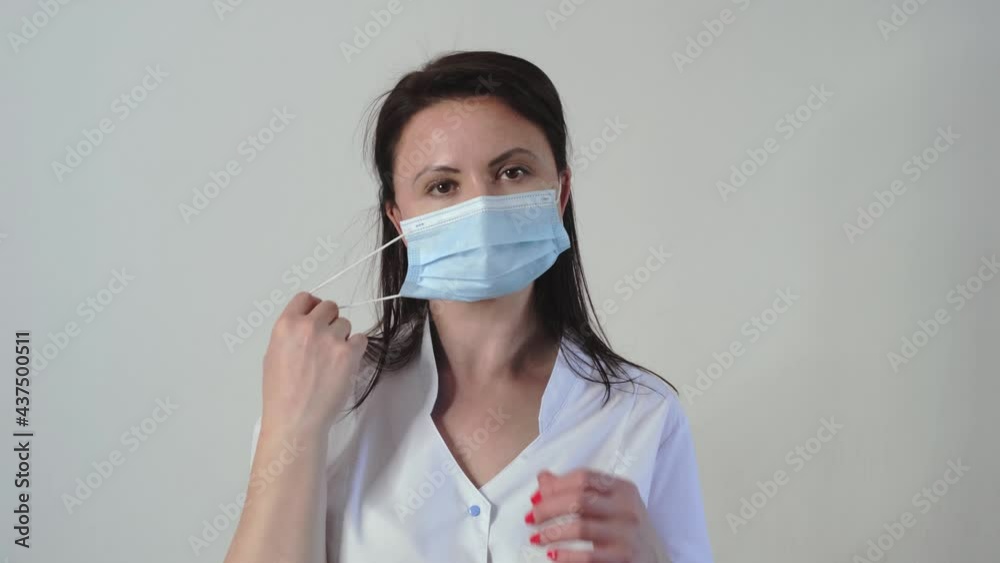 Portrait of young tired caucasian female doctor or nurse putting on face medical mask. Coronavirus prevention concept. Slow motion Portrait of young tired caucasian female doctor or nurse putting on face medical mask. Coronavirus prevention concept. Slow motion