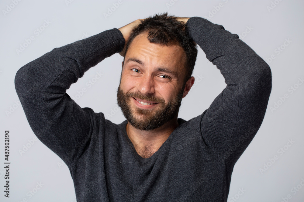 Mature contented man with beard smiling on white background with gray jumper