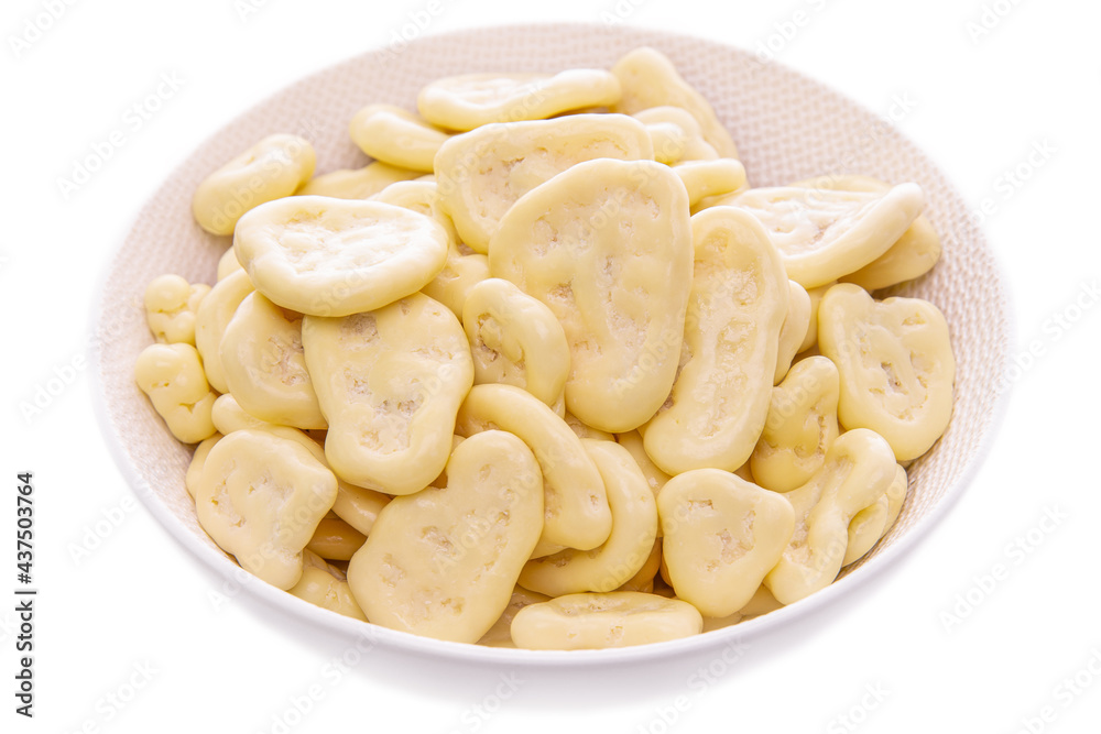 Banana chips in white chocolate, in a white plate on a white background, isolated products Banana chips in white chocolate, in a white plate on a white background, isolated products