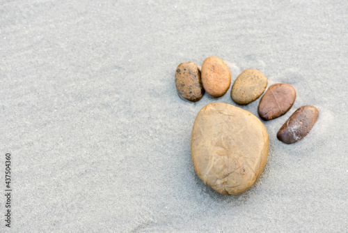 The stones are arranged in the form of feet on sandy beach.