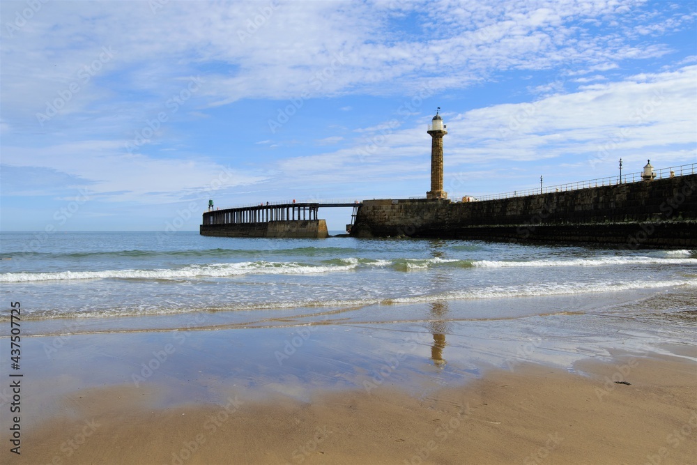 Reflections of the lighthouse, on the West Pier of Whitby beach, North Yorkshire, England.