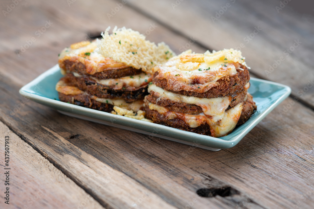 Pan fried crispy eggplant with parmesan cheese crust isolated on wooden table