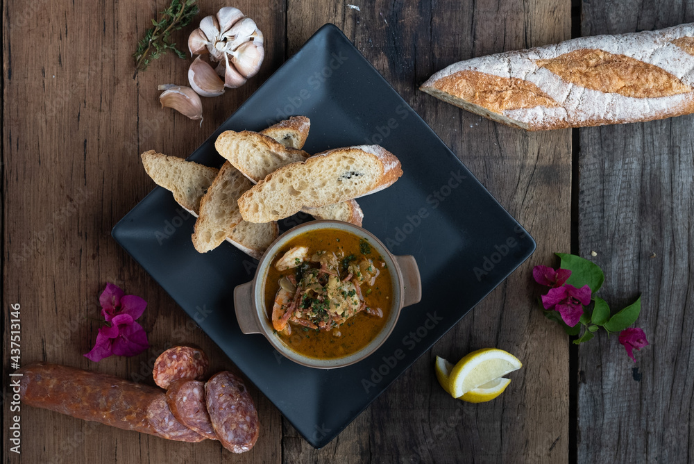 Top view of Gambas Pil Pil - Sizzling prawns with chili and garlic served with bread on the side isolated on wooden rustic table