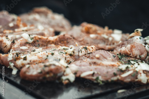 Wonderful detail of grilling pork neck meat on a granite stone laid on the heat of the fire. Meat sprinkled with salt, basil, rubbed with oil. Barbecue season has begun
