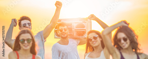 The happy people dancing with a boom box on the sunny background
