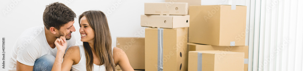 The smile couple sit on the background on the boxes The smile couple sit on the background on the boxes
