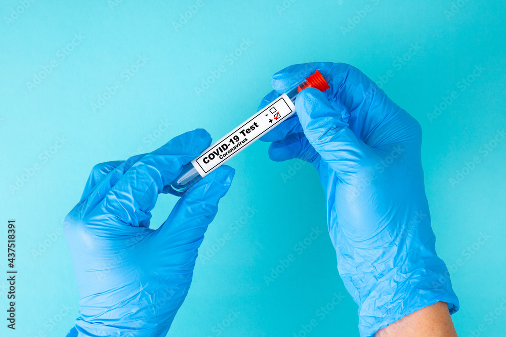 Hand in blue gloves holding a test tube sample with positive COVID-19 virus. Hand in blue gloves holding a test tube sample with positive COVID-19 virus.