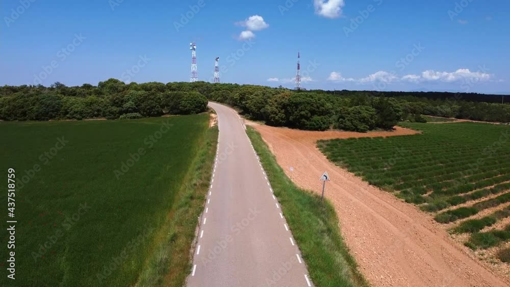 Rural road and telecommunication antennas at the end of a road amidst lavender fields