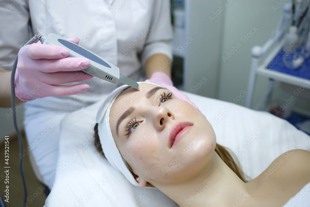 Cosmetologist does ultrasonic cleaning of the face. Women s cosmetology in the beauty salon Cosmetologist does ultrasonic cleaning of the face. Women s cosmetology in the beauty salon